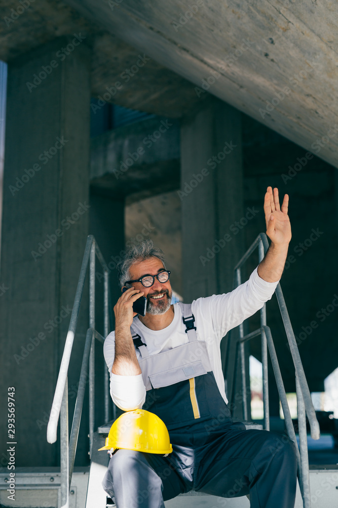 worker talking on smartphone sitting on stairs on site