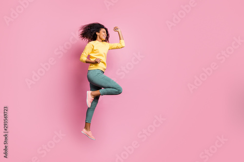 Full size photo of excited cheerful optimistic delightful rejoicing ecstatic crazy glad good hipster enjoying her fortune jumping up raising fists up wear yellow sweater pants isolated background