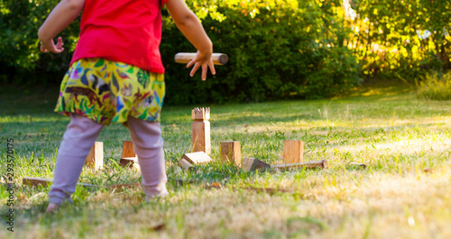 Mädchen spielt Wikingerschach (Kubb). Girl playing Kubb in garden.