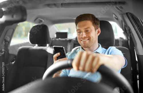 transport, vehicle and technology concept - smiling man or driver driving car and using smartphone © Syda Productions