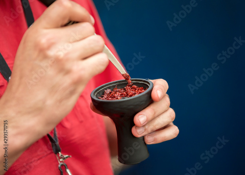 Quadro em tela Close up of man hammering tobacco into hookah bowl outdoor