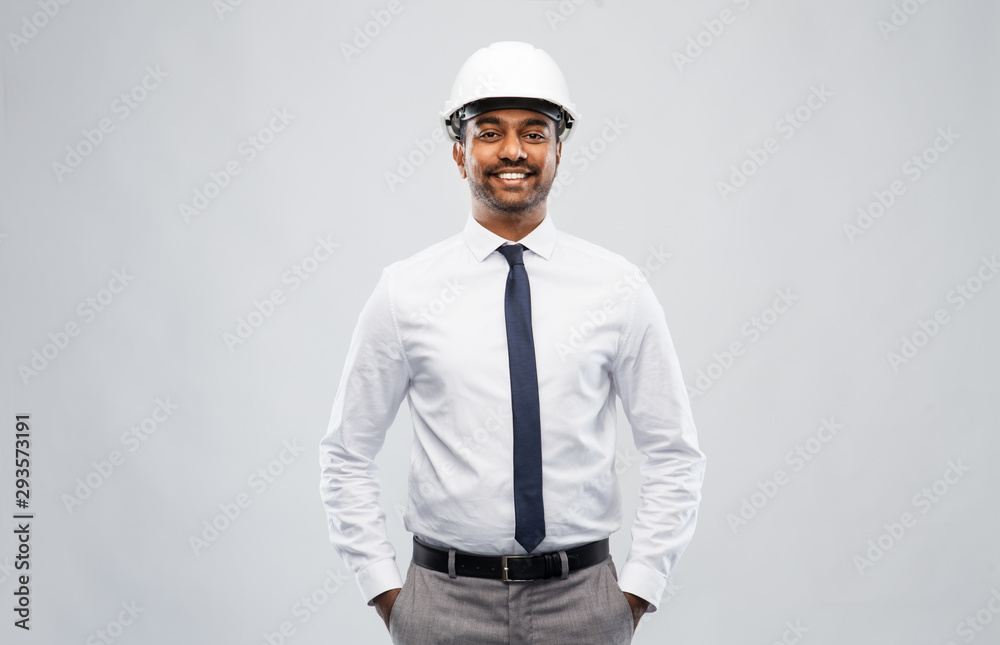 architecture, construction business and people concept - smiling indian male architect in helmet over grey background architecture, construction business and people concept - smiling indian male architect in helmet over grey background