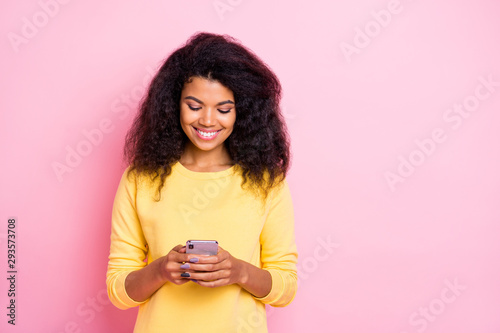 Portrait of positive cheerful black lady feel interested use her cell phone read feednews in social network account wear good looking trend outfit isolated over pastel pink color background photo