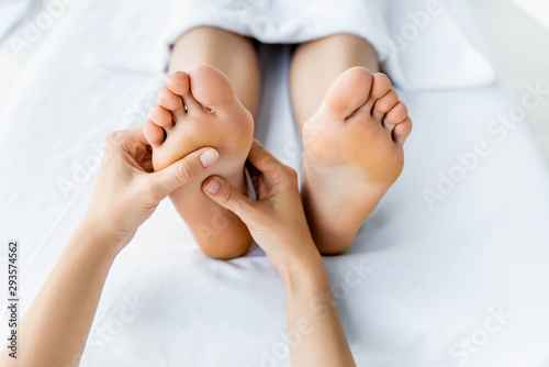 Foto cropped view of masseur doing foot massage to woman in spa