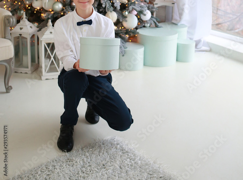 boy with a box andr sits on a New Year’s sofa near the Christmas tree photo