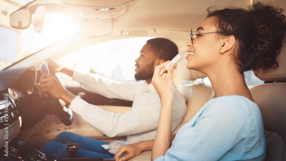 Road trip. Man driving car, girlfriend applying lipstick Road trip. Man driving car, girlfriend applying lipstick