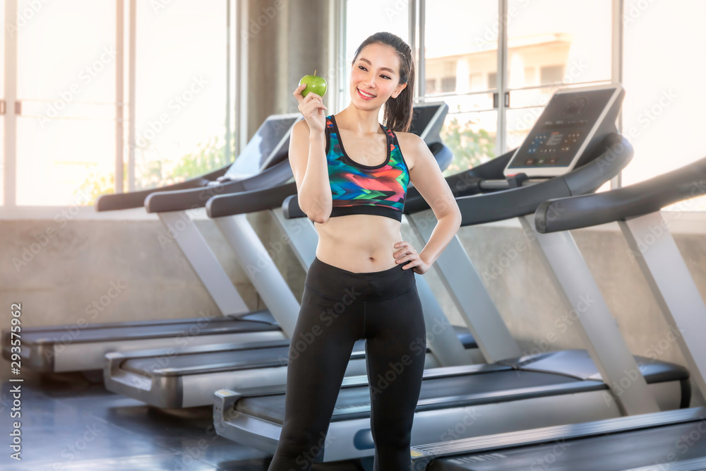 Perfect Asian woman in sportswear holding green apple for eat before workout at fitness gym. Perfect Asian woman in sportswear holding green apple for eat before workout at fitness gym.