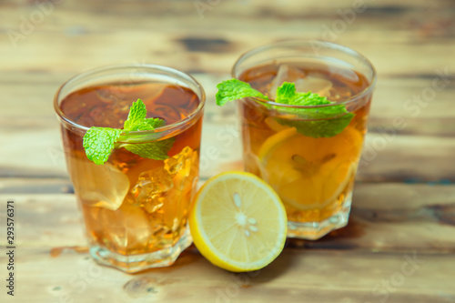 Iced tea with lemon slices and mint on wood background