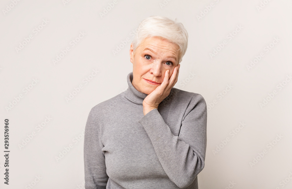 Shocked senior woman holding cheek up in total disbelief Shocked senior woman holding cheek up in total disbelief