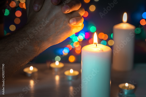 pray with lit candles. Prayer and meditation at candle flames. Symbol of eternity and remembrance of the dead. Religious tradition. Bokeh background.