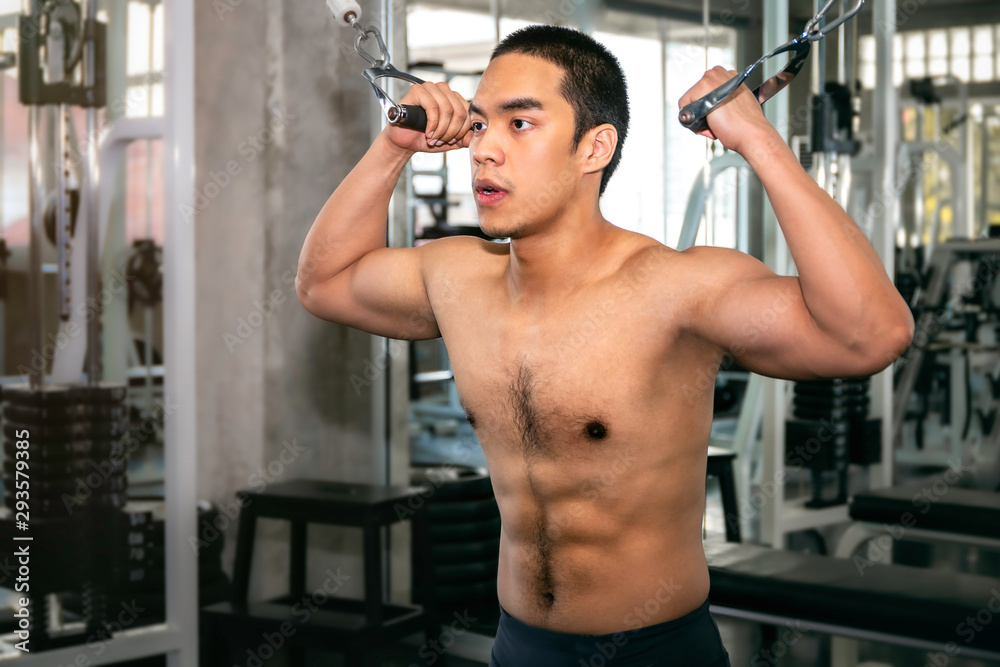 Handsome strong bodybuilder athletic Asian man workout arm with cable in fitness gym. Handsome strong bodybuilder athletic Asian man workout arm with cable in fitness gym.