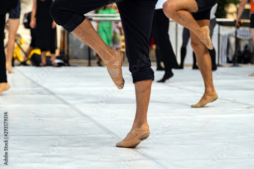 Ballet dancers practicing performance outdoors. Close up of ballerina feet wearing slippers practice moves in ballet class outside