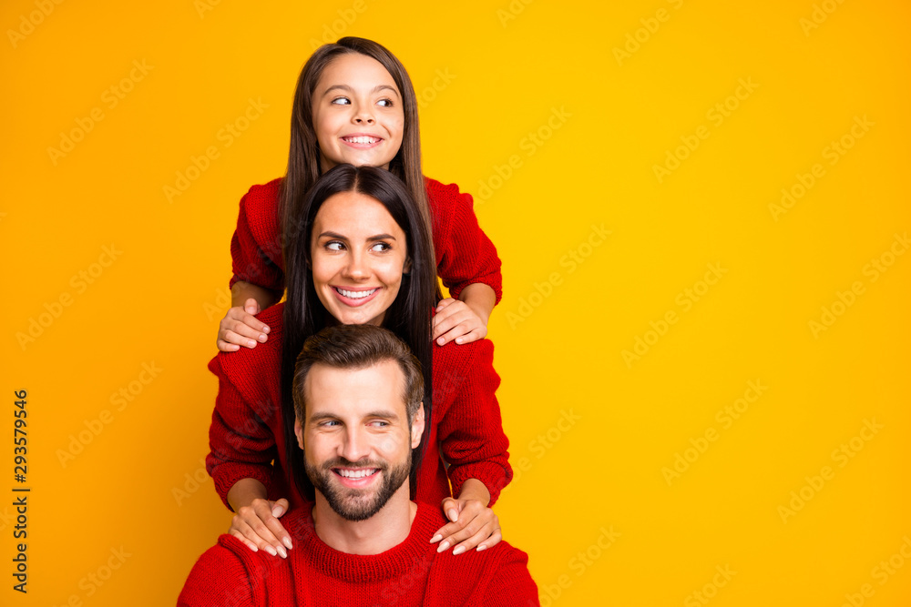 Photo of cute cheerful funny funky family having created pyramid looking away at empty space smiling wearing red sweater toothily isolated over vivid color background