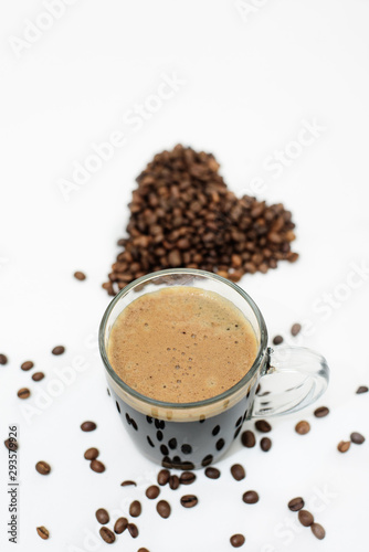 a Cup of fresh coffee and a heart made of coffee beans on a white background © Taranova_ksenya