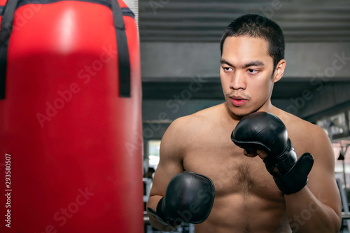Athletes Asian man boxer training on a punching bag at fitness gym. © Suthiporn