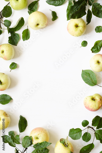 Fresh apples green leaves on white wooden background