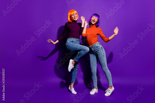 Full length body size view of two nice attractive charming cheerful excited glad girls wearing wigs dancing having fun isolated over bright vivid shine vibrant purple violet lilac color background