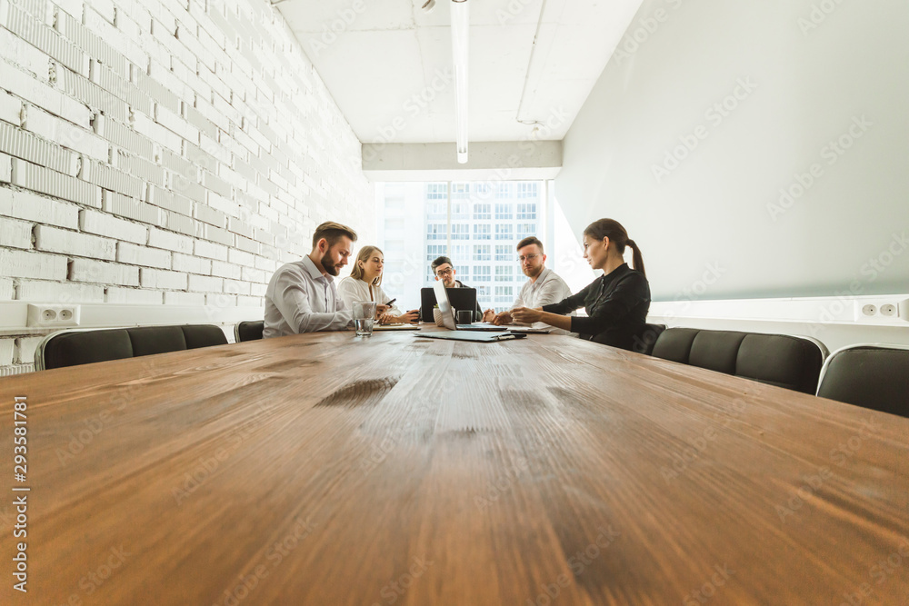 Obraz premium A team of young businessmen working and communicating together in an office. Corporate businessteam and manager in a meeting.