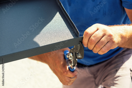 Worker cutting the sheet metal flashing with hands scissors photo