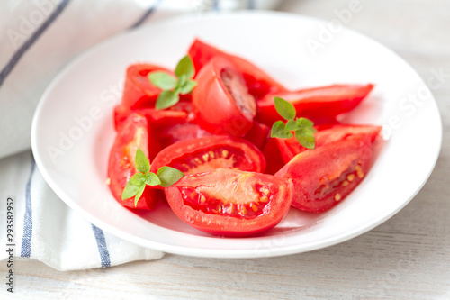 Tomato salad with basil and olive oil, white wooden background. Concept healthy meal. Vegan food. 