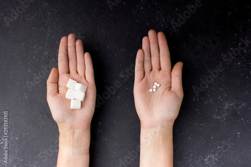  Female hands with sugar and pills on a gray-black background. The choice of sweetener in tablets or regular sugar. An alternative to sugar for diabetics. photo