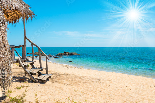 Fototapeta Naklejka Na Ścianę i Meble -  View of sand beach, sea, sun on blue sky and bungalow on tropical island