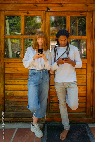 Young multiracial couple using their mobile phone on a wooden background.