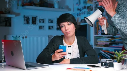 Communication problem. Young man tries to overcome a communication problem by shouting to woman through a megaphone directly into her ear, hoping to make himself heard.