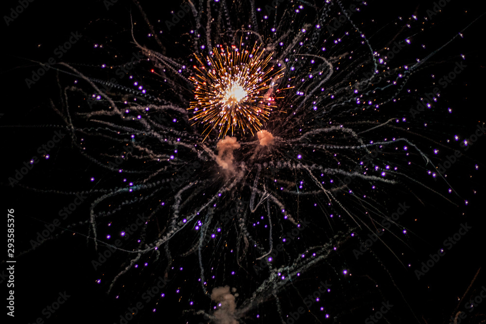Salute in the sky. Explosions of pyrotechnics in the air. Holiday background on the street in the form of a firework. Sparks on the background of the night sky. The city celebrates and launches rocket Salute in the sky. Explosions of pyrotechnics in the air. Holiday background on the street in the form of a firework. Sparks on the background of the night sky. The city celebrates and launches rocket