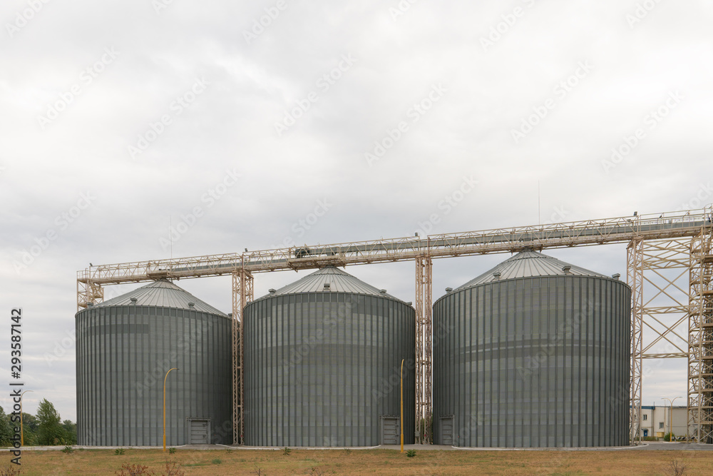 Modern elevator for storing grain against the sky. Grain drying complex, storage and transportation of grain. Large granary in the field. Agricultural industry Modern elevator for storing grain against the sky. Grain drying complex, storage and transportation of grain. Large granary in the field. Agricultural industry