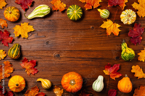 Wooden background. Arranged autumn leaves and pumpkins. Top view.