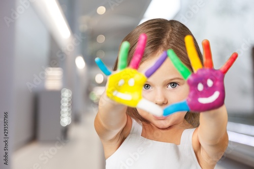 Cute little girl with colorful painted hands on background