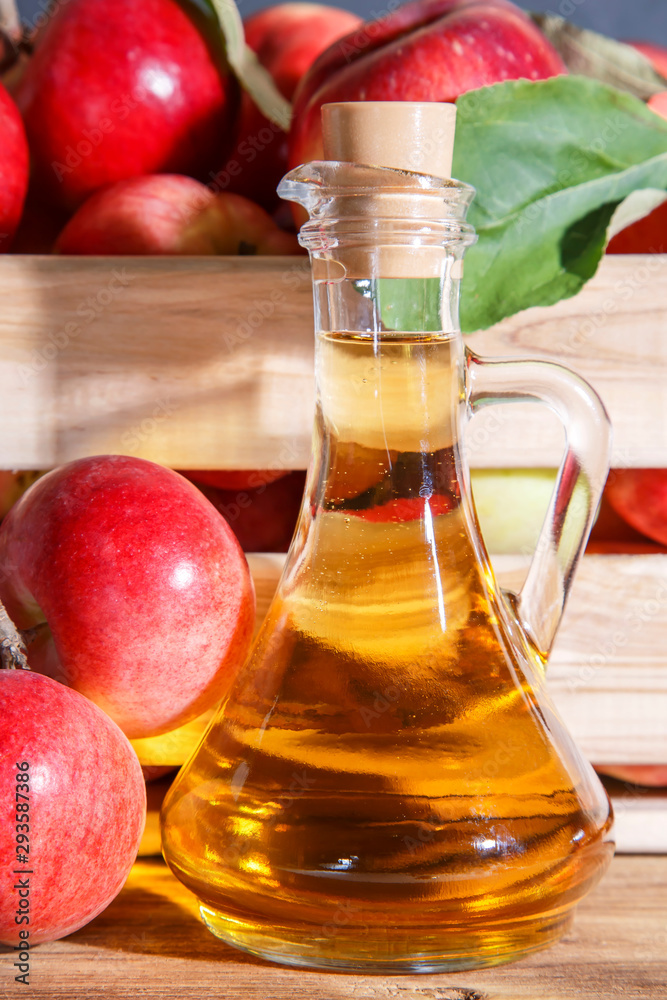 Homemade fruit canning, diet healthy food and drink. Apple cider vinegar, juice, salad dressing from a crop of ripe red garden fruits in a glass jug on a wooden rustic background Homemade fruit canning, diet healthy food and drink. Apple cider vinegar, juice, salad dressing from a crop of ripe red garden fruits in a glass jug on a wooden rustic background