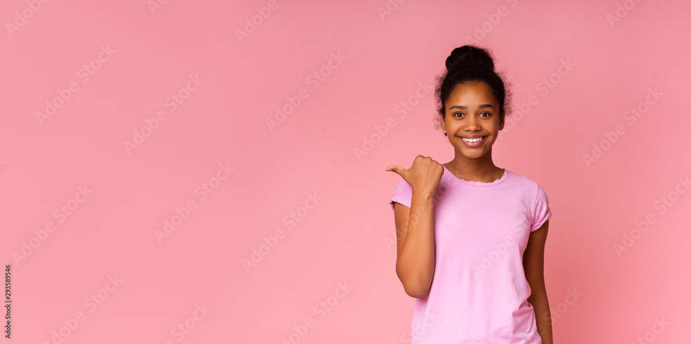 Beautiful african girl pointing at copy space with her thumb