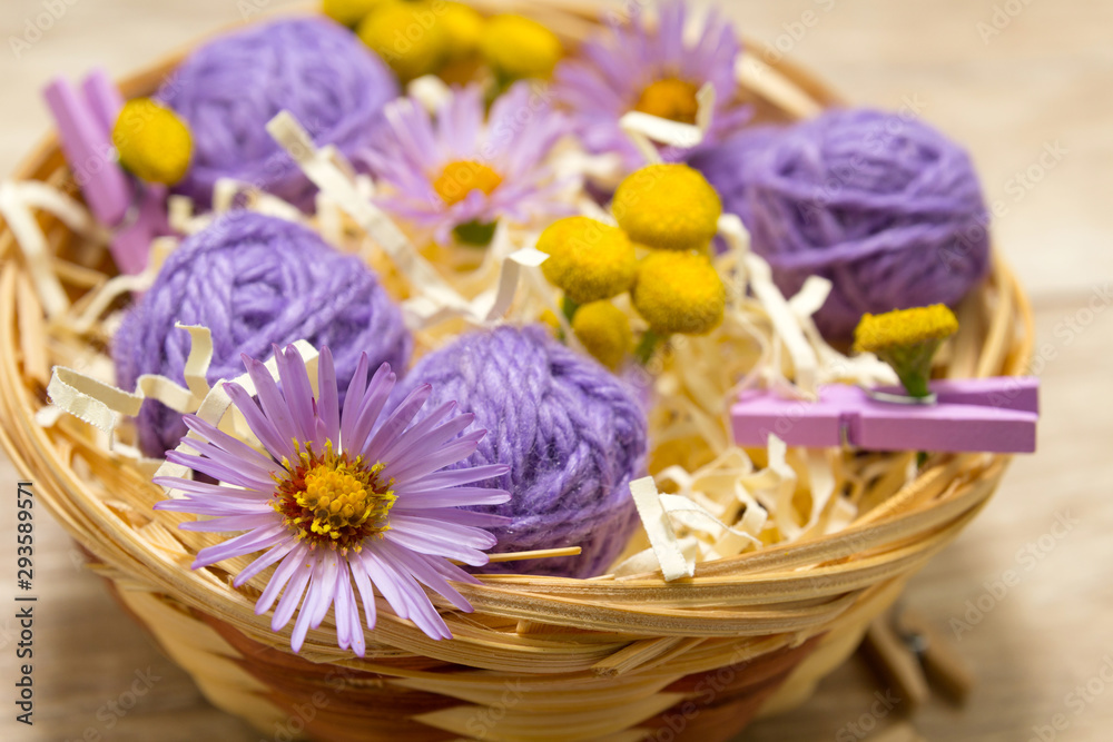 Balls of thread in a straw basket on a wooden table. Mother's day concept. Scenery for Valentine's Day. Vibes of kindness and love Balls of thread in a straw basket on a wooden table. Mother's day concept. Scenery for Valentine's Day. Vibes of kindness and love