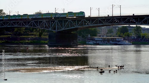 Bridge over the river. Vistulan boulevards on the western side of the River Vistula in Warsaw and trains crossing a river bridge. photo