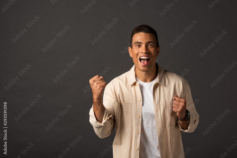 excited handsome mixed race man in beige shirt showing yes gesture on black background excited handsome mixed race man in beige shirt showing yes gesture on black background