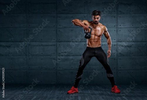 Handsome Bodybuilder Exercising With Kettlebell. Copy Space for text