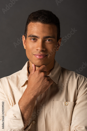 Photos portrait of smiling handsome mixed race man in beige shirt on black background