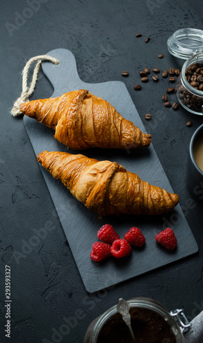 Croissant z malinami leżący na kamiennej desce. Ciemne tło, widok z góry. photo