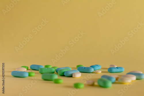 Colored medications on yellow neutral background. Concept of prescription drug abuse. Products of the pharmaceutical industry