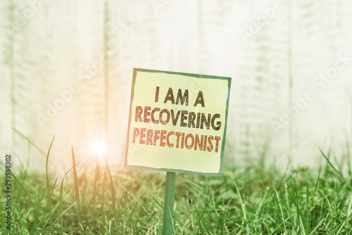 Conceptual hand writing showing I Am A Recovering Perfectionist. Concept meaning Obsessive compulsive disorder recovery Plain paper attached to stick and placed in the grassy land
