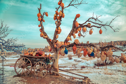 Decorative jugs on a tree and an old cart.