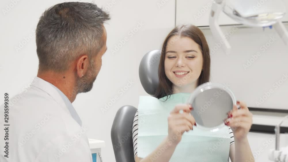 Beautiful happy woman talking to the dentist after medical checkup. Charming female patient at the dental clinic, talking to her doctor. Whitening, dentistry concept Beautiful happy woman talking to the dentist after medical checkup. Charming female patient at the dental clinic, talking to her doctor. Whitening, dentistry concept