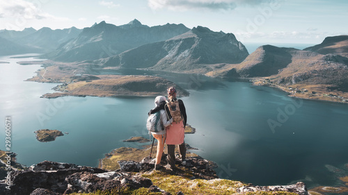 Платно A couple of young people in love stand hugging on top of the Voladstinden mountain in Lofoten islands in Norway