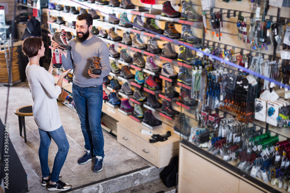 Positive couple examining various shoes in sports store