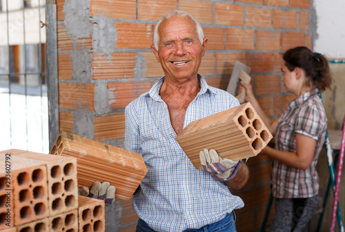 Man with woman installing brick wall