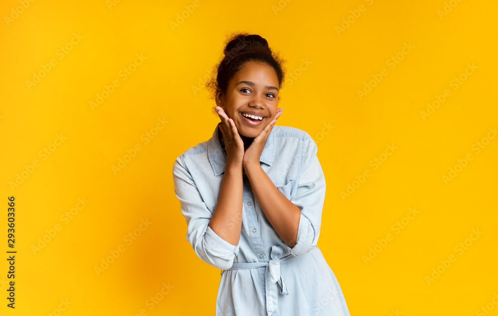 Excited black schoolgirl smiling on camera and touching her face Excited black schoolgirl smiling on camera and touching her face