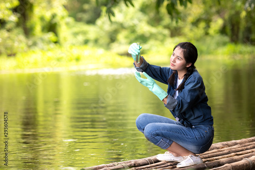 Fototapeta Asian student biology taking and testing sample of natural river water