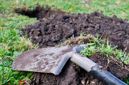 Close-up shovel digs hole in meadow